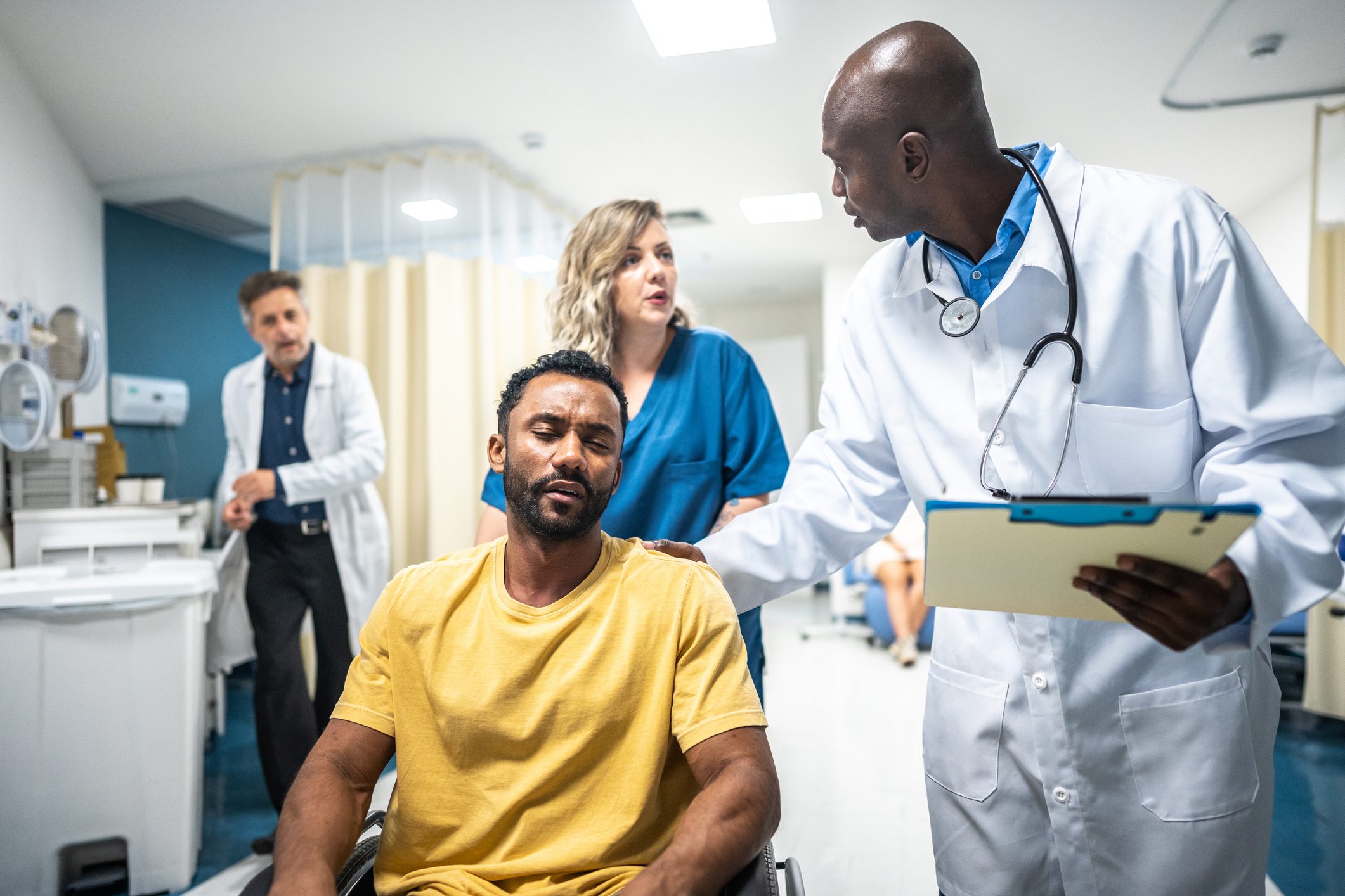 Nurse pushing patient in a wheelchair while doctor talks to him in the hospital